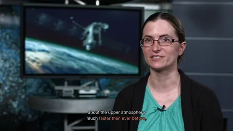 The word FASTER appears behind a NASA scientist as she says it, its last letter tucked behind her head